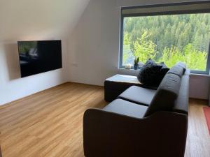 a living room with a couch and a large window at Haus Adler - Komplettes Ferienhaus am Badesee in Erzgrube