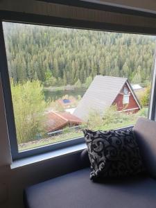 een raam met uitzicht op een huis en een bos bij Haus Adler - Komplettes Ferienhaus am Badesee in Erzgrube