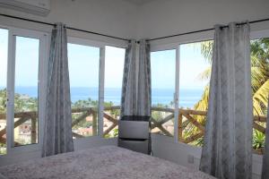 a bedroom with a bed and large windows with the ocean at Posada Las Graditas in Sayulita