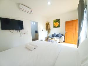 a white bedroom with a bed and a tv at Abams Gili Air in Gili Air