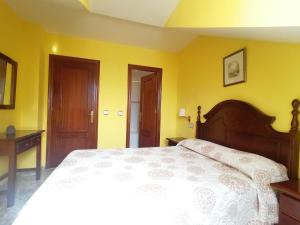 a bedroom with a white bed and yellow walls at Hotel Las Palmeras Celorio in Llanes