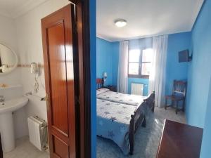 a bedroom with a bed and a bathroom with a sink at Hotel Las Palmeras Celorio in Llanes