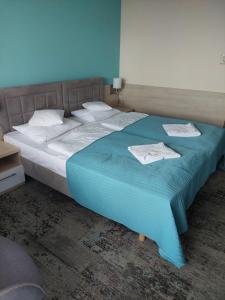 a bed with a blue blanket and white pillows at Apartament Nad Parsętą in Kołobrzeg