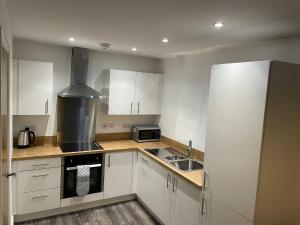 a kitchen with white cabinets and a stove top oven at Queens Apartment - Lovely entire apartment in Sheffield