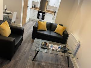 a living room with a black couch and a table at Queens Apartment - Lovely entire apartment in Sheffield