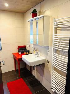 a bathroom with a white sink and a red table at Ferienwohnung Burgblick in Schramberg +21 photos