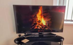 a flat screen tv with a fire in the background at The Lawrence, 2 Bedroom Victorian House in Redcar