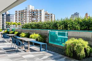 uma piscina com mesas, cadeiras e edifícios em Studio Excelente no Pátio Milano #CA03 em Florianópolis