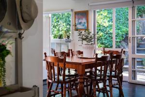 a wooden table and chairs in a room with windows at Storybook Cottage-surrounded by beautiful gardens in Daylesford