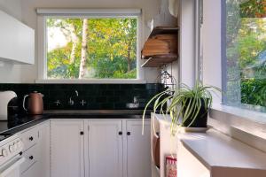 a kitchen with white cabinets and a window at Storybook Cottage-surrounded by beautiful gardens in Daylesford +6 photos