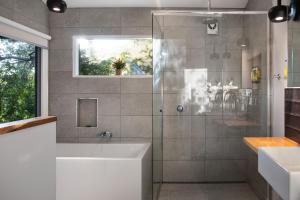 a bathroom with a shower with a tub and a sink at Storybook Cottage-surrounded by beautiful gardens in Daylesford