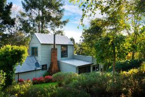 a white house with a brick chimney in the yard at Storybook Cottage-surrounded by beautiful gardens in Daylesford