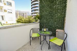een tafel en stoelen op een balkon met een groene muur bij Apartment near Old Town in Budva