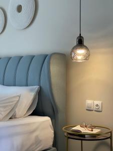 ein Bett mit einem blauen Kopfteil und einem Tisch mit Brille darauf in der Unterkunft Helen Hotel in Poros