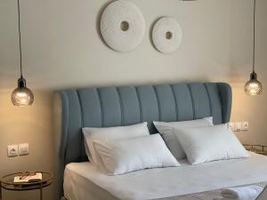 a bed with a blue headboard and white pillows at Helen Hotel in Poros