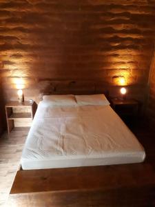 a bed in a wooden room with two night lights at Chalés Portal Verde - Seja bem vindo in Carrancas