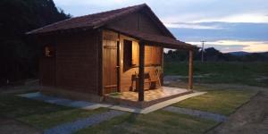 a small building with a porch in a field at Chalés Portal Verde - Seja bem vindo in Carrancas