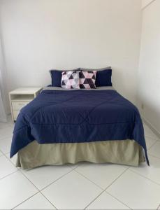 a bed with a blue comforter and a pillow on it at Apartamento Praia in Guarujá