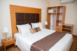 Schlafzimmer mit einem großen weißen Bett mit einem Kopfteil aus Holz in der Unterkunft Ndaru Luxury suites in Kigali