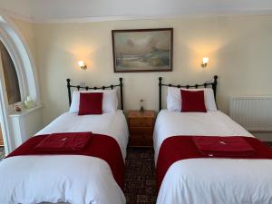 two beds in a room with red and white sheets at Knighton Lodge in Skegness