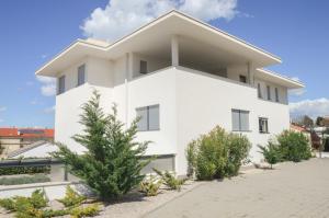 a white building with trees in front of it at Rova Apartment in Malinska