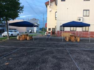 Deux tables de pique-nique avec des parasols bleus dans un parking dans l'établissement Homestay Dream - Vacation STAY 3910, à Minami Uonuma