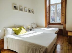 2 camas en una habitación con 2 ventanas en Casa da Praça Square Suites en Coimbra