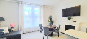 a living room with a table and a couch and a television at Spacious 3 bed flat near the sea with parking in Bournemouth