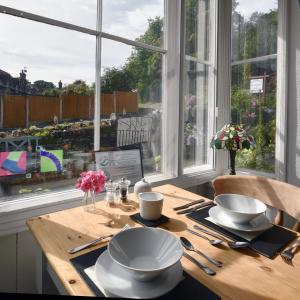 einen Tisch mit Tellern und Küchenutensilien in einem Zimmer mit Fenster in der Unterkunft Garth Dderwen in Betws-y-coed