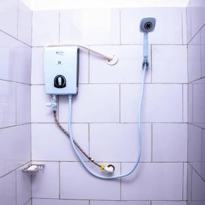 una ducha con una manguera pegada a una pared de azulejos blancos en Sereneville 4 Deluxe Bukoto-Kisaasi Apartment, en Kampala
