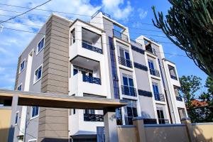 un edificio blanco con persianas azules en Sereneville 4 Deluxe Bukoto-Kisaasi Apartment, en Kampala