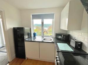 a kitchen with a sink and a black refrigerator at Superb Garden Suite at The Moorings Shaldon in Shaldon