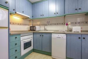 a kitchen with blue cabinets and white appliances at Villas Guzman - Apartamento Trond Paraiso Mar in Calpe