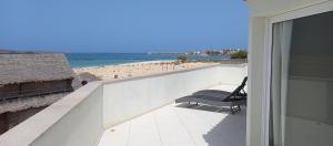 Un balcón con un banco y vista a la playa. en KatlantiK Beach House Deluxe, en Sal Rei