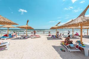 a group of people sitting on a beach with umbrellas at L&C BEACH HOME by ZORA Rezidential - PE PLAJA in Mamaia Sat/Năvodari