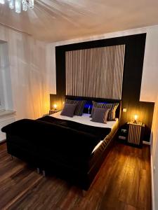 a bedroom with a large black bed and two lamps at Am Stephanswäldchen in Kamp-Lintfort