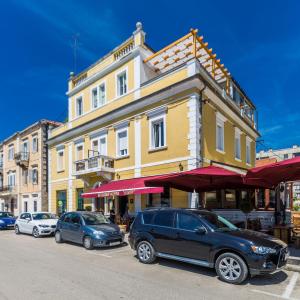a large yellow building with cars parked in front of it at B&B Giardin exclusive rooms and suite in Zadar