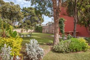 a garden with a red wall and a bench at Il TRAMONTO in San Antonio de Areco