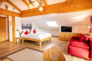 a bedroom with a bed and a red couch at Alphirt Ferienwohnungen in Fischen