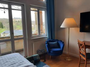 a room with a bed and a chair and a window at Hotel Villa Viktoria Luise in Blankenburg
