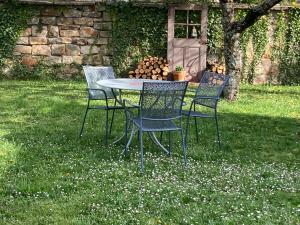 three chairs and a table in the grass at Maison Alsacienne Typique Gite Weiss in Gunstett