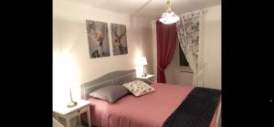 ein Schlafzimmer mit einem rosa Bett und zwei Bildern an der Wand in der Unterkunft Appartement dans uns corps de ferme in Follainville-Dennemont