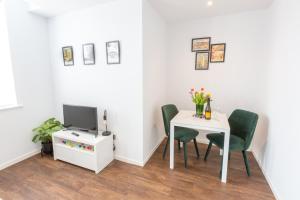 Chester Stays - Lovely apartment in the heart of Chester with free parking في تشيستر: غرفة طعام مع طاولة وكراسي وتلفزيون