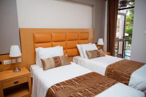 Habitación de hotel con 2 camas y ventana en Ndaru Luxury suites, en Kigali