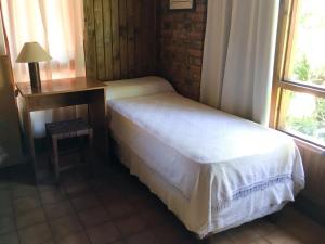 a bedroom with a bed and a table and a window at Hosteria Helvecia in Montecarlo