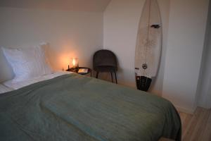 a bedroom with a bed and a surfboard on the wall at Viking Surf House in Klitmøller