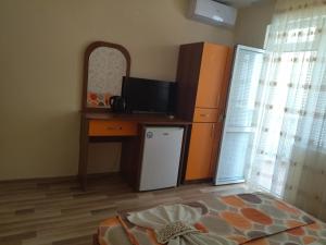 a room with a refrigerator and a desk with a television at Фамилна къща Джоко in Kiten