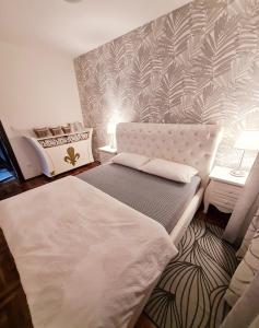 a bedroom with a bed and a wall with palm leaves at Lux Apartman Ristić 1 in Soko Banja