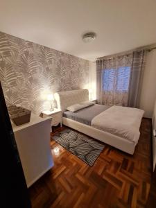 a bedroom with a bed and a table and a window at Lux Apartman Ristić 1 in Soko Banja