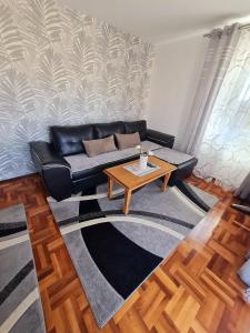 a living room with a black couch and a coffee table at Lux Apartman Ristić 1 in Soko Banja